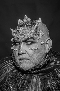 Şeytan siyah zemin üzerine altın yakalı. Adam dikenler veya siğiller ile yüz pırıltılar ile kaplı. Beyaz sakallı komuta sizde canavar gibi giyinmiş. Uzaylı, iblis büyücü makyaj. Fantezi kavramı.