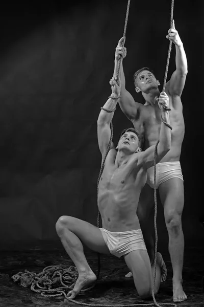 The two twins gymnastic acrobatic caucasian men on rope.