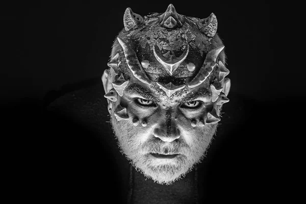 Alien, demon, sorcerer makeup. Head with thorns or warts, face covered with glitters, close up. Fantasy concept. Demon on serious face, black background. Senior man with beard, with monster makeup.