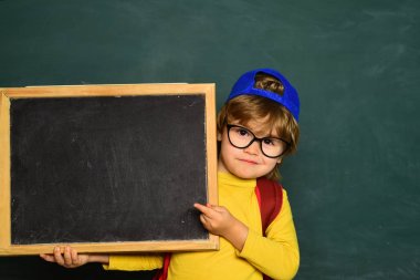 Masada mutlu gülümseyen öğrenciler çiziyor. Tahtadaki neşeli gülümseyen çocuk. Sınıf odası. 1 Eylül. Okula geri dön..