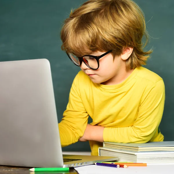 Leuke jongen met vrolijke gezichtsuitdrukking bij het bureau met schoolspullen. Privé school. Lerarendag. Klaar voor school. Schoolconcept. — Stockfoto