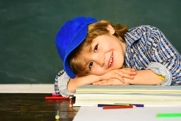 Cute little preschool kid boy in a classroom. Schoolchild. Happy mood smiling broadly in school. Schoolboy. Elementary school and education. First school day. — Stock Photo, Image