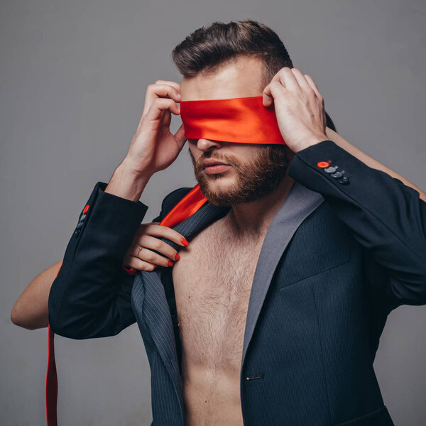 Разбудил его желание. Мужчина-дразнилка. Мачо хорошо ухоженный бородатый хипстер завязал глаза красной лентой. Сексуальные отношения. Секс-игра. Дразнить и соблазнить. Страстные любовники. Сексуальное доминирование. Сексуальное подчинение
