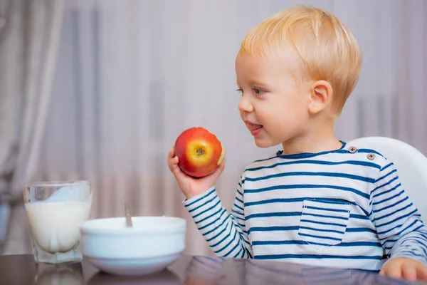 Kind eet PAP. Kid cute Boy blauwe ogen zitten aan tafel met plaat en voedsel. Gezonde voeding. Jongen schattig baby eten ontbijt. Baby voeding. Gezond eten. Peuter met snack thuis. Gezonde voeding — Stockfoto