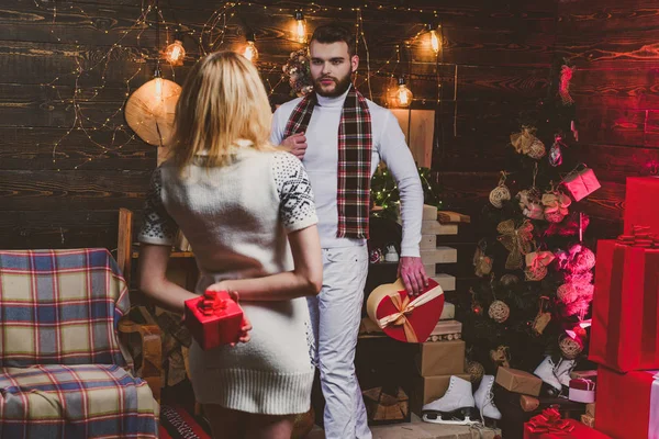 幸せなブロンドの若い女性と男性は、お互いにクリスマスプレゼントを与えています。素敵な幸せなカップル。ハピネスクリスマスツリーの背景. — ストック写真