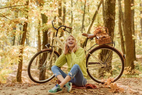 음악 일시 정지. 금발은 숲을 휴식 즐길 수 있습니다. 따뜻한 가을. 자전거와 헤드폰을 가진 소녀. 자전거 가을 숲을 가진 여자입니다. 주말 활동. 활동적인 레저 및 라이프 스타일. 재미를 위해 자전거를 타고 소녀 — 스톡 사진