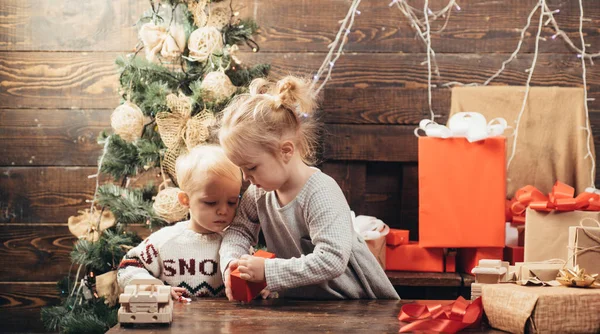 Niedliches kleines Mädchen schmückt den Weihnachtsbaum drinnen. am Morgen vor Weihnachten. Kinder genießen den Urlaub. fröhliches süßes Kind öffnet ein Weihnachtsgeschenk. — Stockfoto