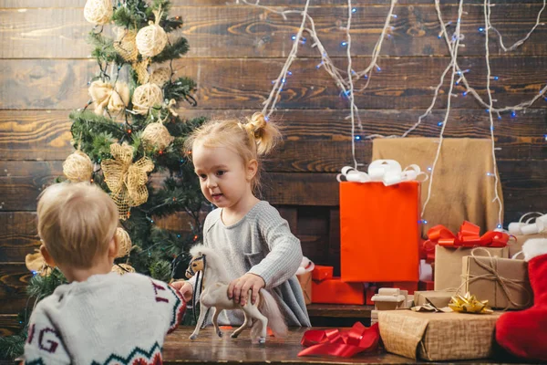 Забавный ребенок держит рождественский подарок. Рождественские дети. Милый маленький ребенок украшает елку в помещении. Детское Рождество . — стоковое фото