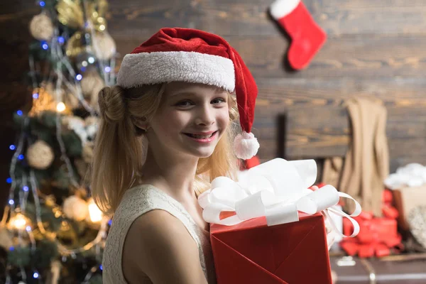 Çocuk hediyesi. Noel ağacının yanındaki sevimli küçük kız. Ahşap arka planda hediye olan portre çocuğu. Çocuk tatilin tadını çıkar. Mutlu Noeller ve Mutlu Yıllar. — Stok fotoğraf