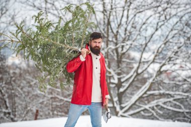 Kış ormanında baltayla oduncu. Kış manzarası. Uzun sakallı, Noel Baba hipster kışın arka planda poz veriyor. Mutlu Noeller ve mutlu yıllar..