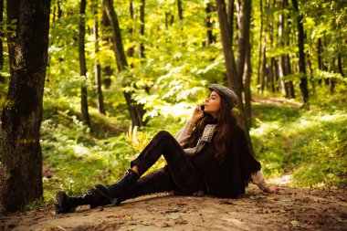 Romantik Sonbahar Kadın Modeli. Fall Maple Leaf Outdoor ile mükemmel kadın modası modeli. Sarı Ağaçlar ve Yapraklar. Sonbahar kırmızı elbiseli güzel moda kadını doğanın arka planında yapraklar dökülüyor..
