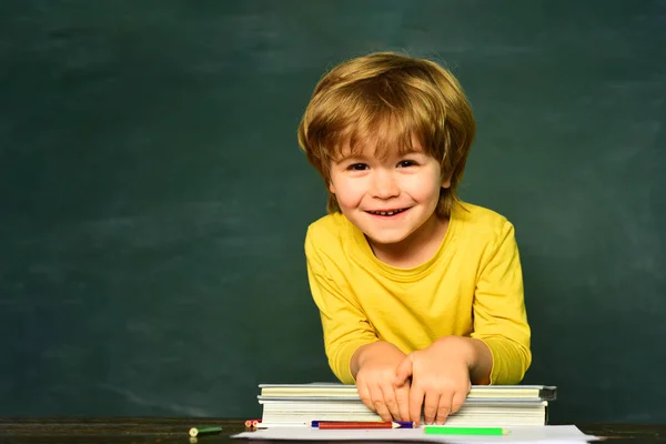 Escuela Primaria. Feliz humor sonriendo ampliamente en la escuela. Primer día de escuela. El niño está aprendiendo en clase en el fondo de la pizarra —  Fotos de Stock