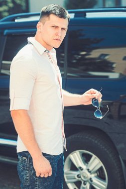 Sürücü hazır yakınındaki şehir sokak araba. Şık giysiler açık güneşli üzerinde iş adamı. Otomobil taşıma adam. Seyahat ve ulaşım kavramı