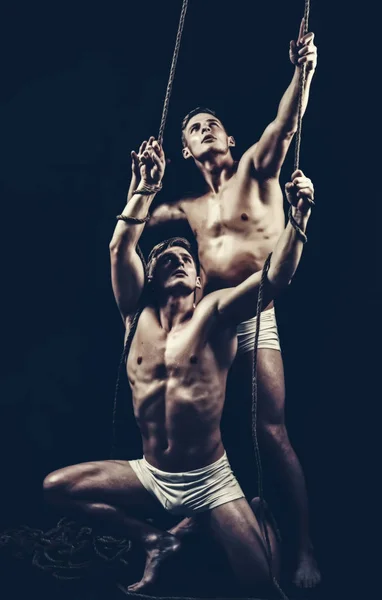 Twee tweelingen mannen doen yoga partners in een sportschool met touw — Stockfoto
