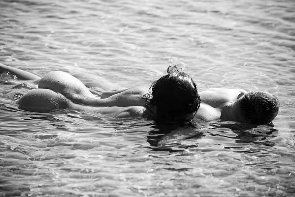 Jovem casal sexy na praia com sol nascente . — Fotografia de Stock