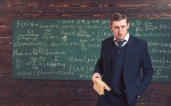 Profesor ansioso mirando por encima de sus gafas. Un hombre inteligente con traje sosteniendo el libro en clase. Concepto universitario Elite —  Fotos de Stock