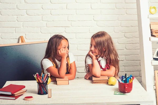 Amistad de las hermanas pequeñas en el aula en el día del conocimiento. Las niñas comen manzana en la hora del almuerzo. niños aburridos de la escuela en la lección en septiembre 1. Hora de la escuela de chicas. Volver a la escuela y a la educación en el hogar — Foto de Stock