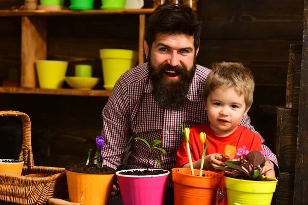 Flower care watering. Soil fertilizers. Father and son. Fathers day. Family day. Greenhouse. bearded man and little boy child love nature. happy gardeners with spring flowers. Water on leaves