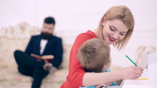 Concept d'enseignement à domicile. Père livre de lecture, tandis que la mère enseigne fils préscolaire pour dessiner ou écrire, intérieur de luxe. Un gamin qui grandit dans l'assistance sociale. Les parents apprécient la parentalité, heureux. Fermer le portret . — Video