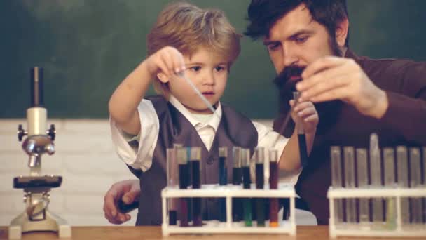 Kimyada öğretilenler. Öğretmen bir öğrenciye mikroskop kullanmayı öğretiyor. Bilim ve eğitim konsepti. Okuldaki küçük çocuklar.. — Stok video