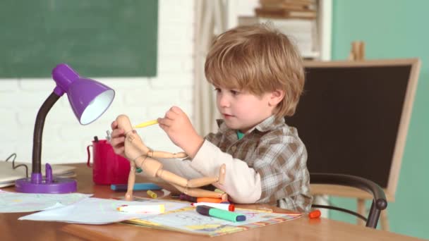 Счастливые улыбающиеся ученики рисуют за партой. 1 сентября. Ребенок учится в классе на фоне доски, школьника. Дети из начальной школы. Маленький мальчик в классе - концепция детского образования . — стоковое видео