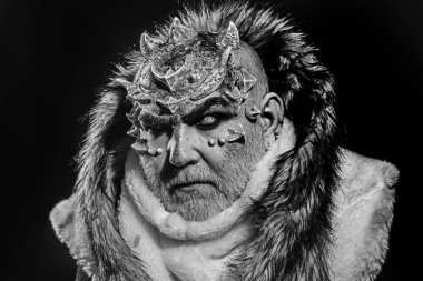 Karanlık sanatlara kavramı. Beyaz sakallı komuta sizde canavar gibi giyinmiş. Siyah arka plan, cehennemdeki şeytanlar kapatın. Dikenler veya siğiller kürk paltolu adam. Uzaylı, iblis, büyücü makyaj.