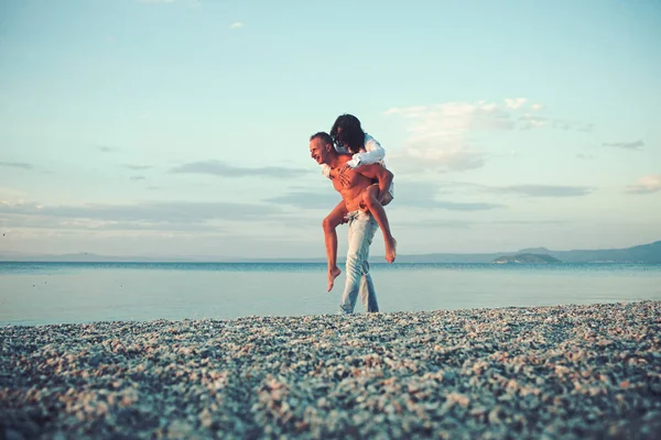 Romântico jovem casal na praia ao pôr do sol . — Fotografia de Stock