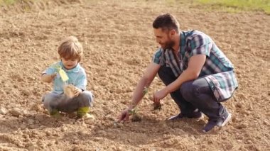 Mutlu baba ve oğul bahar tarlasında dikim. Bahçe aletleri. Eko yaşam - baba ve oğul çiftçi kırsal arka plan ile çiftlikte ekim. Tarım ve tarımsal tarım.