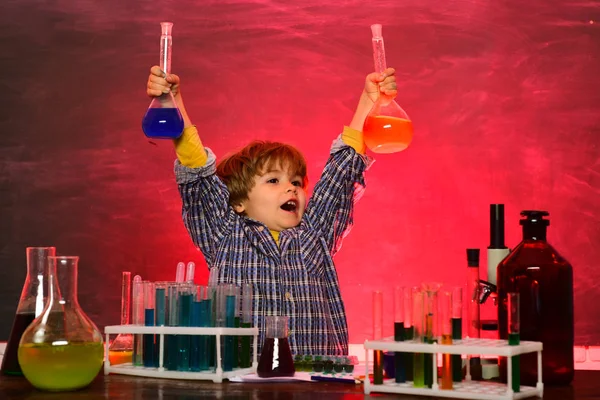 Criança. Aulas de química na escola. Cientista feliz a fazer experiências com tubo de ensaio. Feliz desenho de pupila sorridente na mesa. De volta à escola e à escola doméstica — Fotografia de Stock