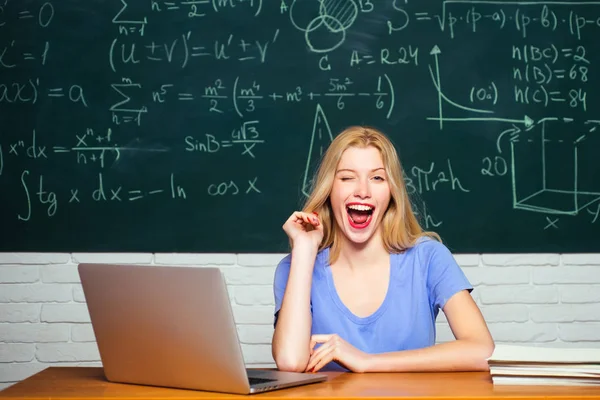 Studentflicka med glada ansiktsuttryck nära skrivbordet med skolmaterial. Tonårselever med skolanteckningsbok. Ung kvinnlig student redo att skriva prov. — Stockfoto
