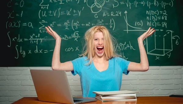 Sıkılmış öğrenci bir dizüstü bilgisayar ile hat üzerinde ev ödevi yapıyor. Öğrenci sınıfta okumaktan yoruldu. Lise. Negatif yüz ifadesi. Dizüstü bilgisayar üzerinde çalışan mutsuz öğrenci. Öğrenme.