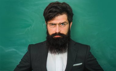 Ciddi erkek öğrenci okulda okuyor. Genç öğretmen. Öğrenme ve eğitim kavramı. Eğitim ve öğrenme insanlar kavramı - kara tahta yakınında kadın Öğretmen.