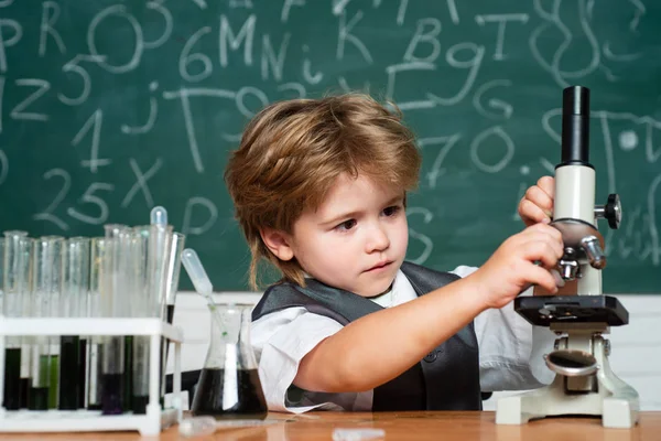 A természettudományi tanterem. Kisgyerek tudós, aki kémiát keres az iskolai laborban. Biológia óra. A srác a táblán tanul az osztályban. Kísérlet. — Stock Fotó