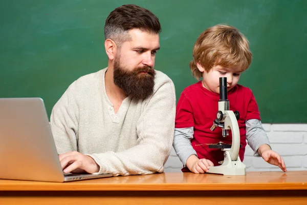 Nauczyciel pomaga uczniom studiować na stanowiskach w klasie. Młody chłopak robi swoją pracę domową ze swoim ojcem. Tło Chalkboard. Tata syn koncentruje się na problemie. — Zdjęcie stockowe