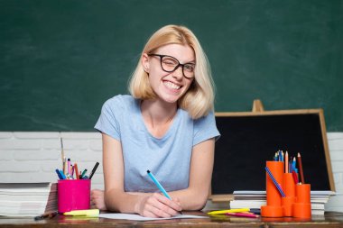 Sınava ya da sınava hazırlanan öğrenci. Kendine güvenen beyaz kadın öğretmenin portresi. Öğrenci ve özel eğitim konsepti. Üniversitede bir kitaptan notlar alan kız öğrenci..