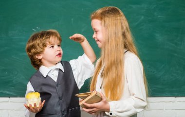 Tahtada neşeli gülümseyen çocuk. Mutlu okul çocukları. Okul dersindeki küçük çocuklar. Sınıfta bir çift küçük kız ve oğlan. Sınıf.