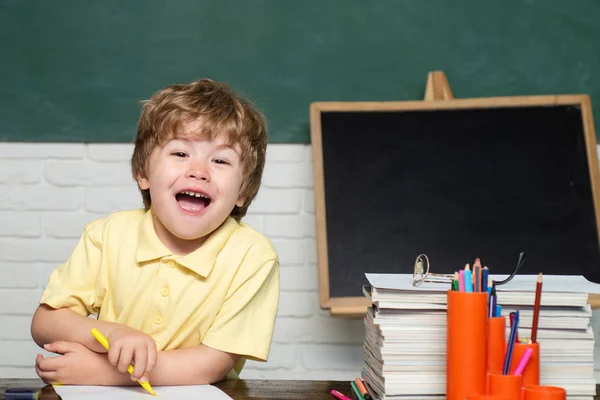 Okula geri dön. Neşeli gülümseyen küçük çocuk Öğrenci kara tahtaya karşı eğleniyor. — Stok fotoğraf