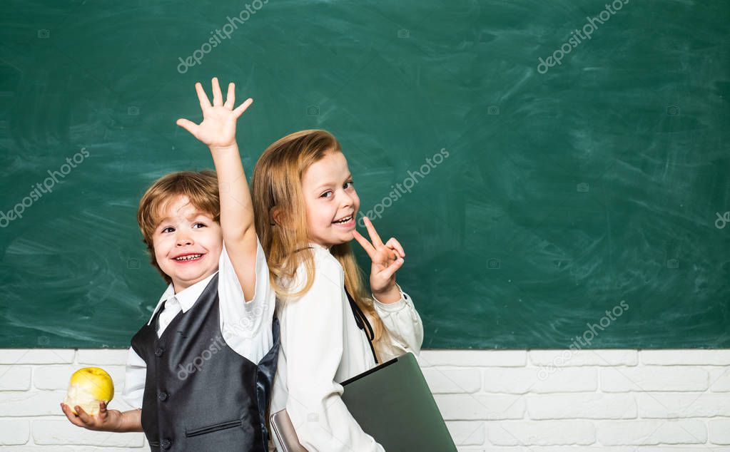 Kid is learning in class on background of blackboard. First grade. Couple of schoolgirl and schoolboy in Love together. Yeah, good work.