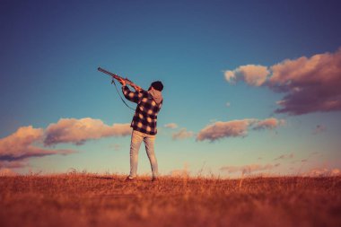 Skeet'in vurulması. Avcı ormanda tüfek doğrulttu. Avcı avda av tüfeği tabancası ile. Sınır tanımayan avlanmak. Ördek avı süreci. Metin için alan kopyalama.