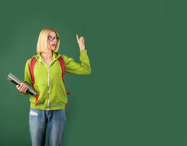 Young happy student. Student studying in the classroom. Happy casual girl student with over blackboard background. Student and tutoring education concept.