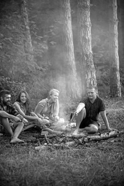 Mutlu arkadaş akşam, arkadaşlık ve eğlence kavramı içinde kamp ateşi etrafında oturan. Genç çiftler ormanda piknik gülümseyerek. Sakallı adam yemek yemek yanıyor