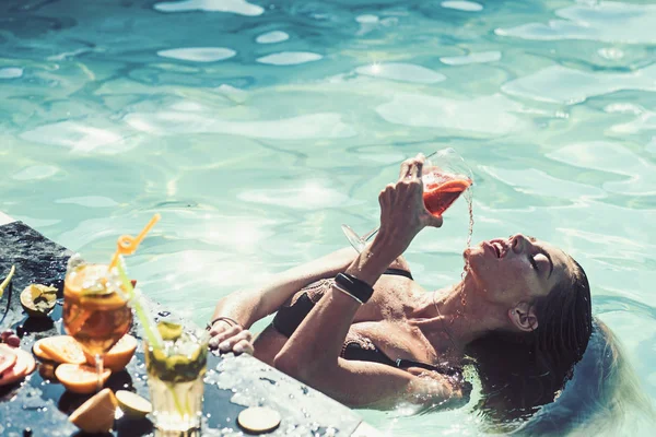 Bella giovane donna sdraiata in acqua con un cocktail in mano . — Foto Stock