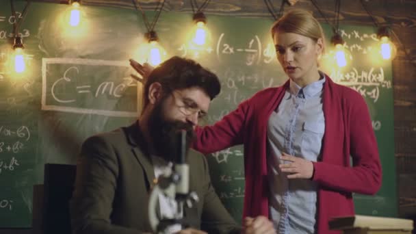 Студентка обговорює з бородатим вчителем в окулярах, що стоять біля зеленої шкільної дошки, на якій написані різні формули. Спільне використання концепції міжнародного друга. Повернутися до школи. Тло . — стокове відео