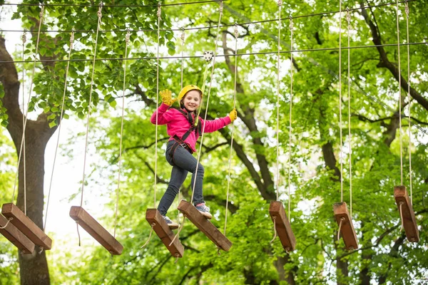 木の中で幸せな子供の登山。ロープ公園。クライマーの子供。幼児期の発達ローピング公園。ビームとロープブリッジのバランスをとる。ロープパーク-クライミングセンター. — ストック写真
