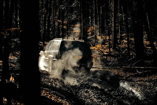 Moção as rodas pneus e off-road que vai para o pó. Jeep bateu em uma poça e pegou um spray de sujeira. Off road caminhão esporte entre montanhas paisagem . — Fotografia de Stock