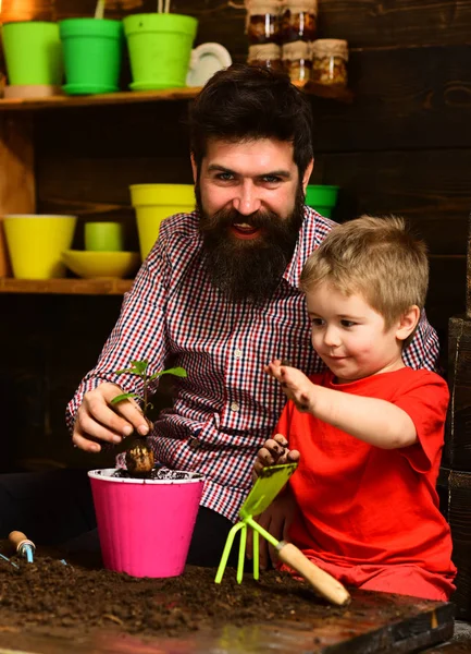 Flower care watering. Soil fertilizers. Family day. Greenhouse. happy gardeners with spring flowers. Father and son. Fathers day. bearded man and little boy child love nature. Fertile present