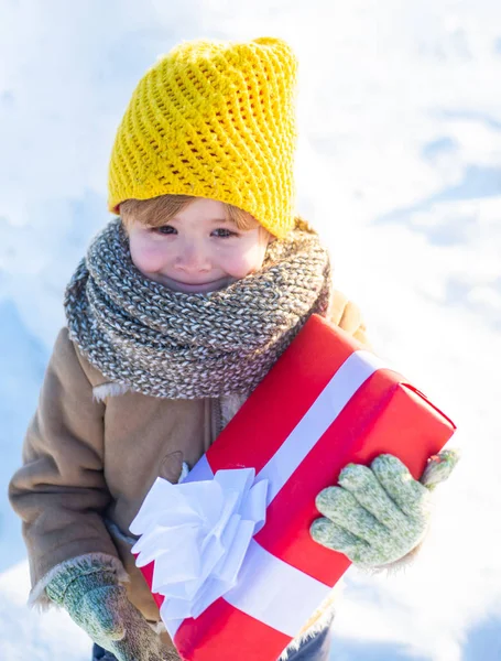 Winter holidays concept. May you have wonderful holiday. Happy winter child hold gift bow snow background. Cute boy in winter clothes hat and scarf close up. Happy new year and merry christmas — ストック写真