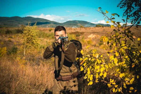 Jäger mit leistungsstarkem Gewehr mit Zielfernrohr, das Tiere beobachtet. Jäger mit Gewehr auf Jagd. Spurensuche. Jagd auf Hirsche. — Stockfoto