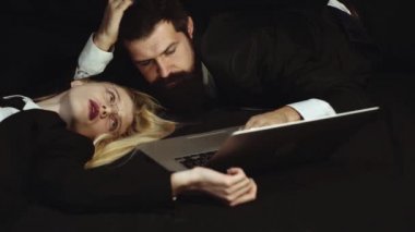Dizüstü bilgisayar kullanarak Iş çift - bağımlısı. Yakışıklı adam ve siyah arka plan üzerinde güzel bir kadın - Sosyal bağımlısı. İşyerinde romantizm numarası. İleti yazma. Sosyal medya.