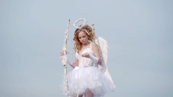 Ημέρα του Αγίου Βαλεντίνου. Το κορίτσι των αγγέλων με άσπρα φτερά. Γλυκιά Αγγελική κοπέλα. Ένα μικρό αγγελούδι εναντίον του ηλιόλουστου ουρανού. Έφηβος άγγελος. Ωραία και χαριτωμένα νιάτα. Έρωτας χαριτωμένο κορίτσι με ένα τόξο — Αρχείο Βίντεο